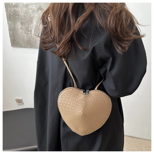 Detail of heart-shaped crossbody bag with crocodile texture and dual zippers