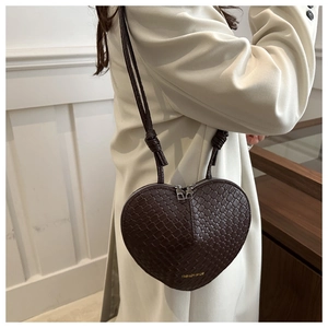 Detailed close-up of dark brown woven heart-shaped leather crossbody bag with dual zippers