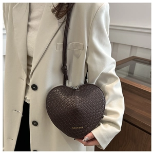 Detail of heart-shaped crossbody bag with woven texture and Fashion Bags print