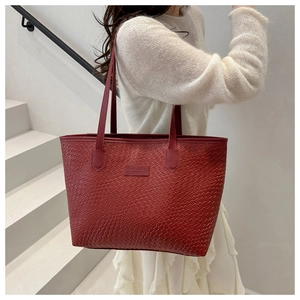 Detail view of red woven texture leather tote bag with FANYISSA brand label on handle