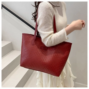 Detail of dark red woven texture on a large tote bag worn by a model in casual attire