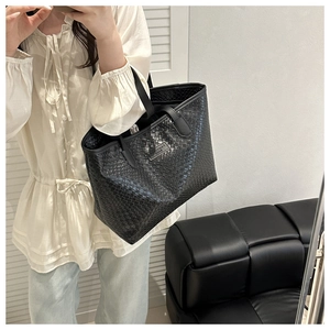 Detail of black woven texture on large tote bag with silver metal logo plaque