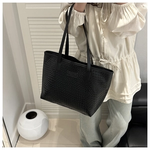 Dettaglio della trama intrecciata e toppa in pelle su una borsa tote nera capiente