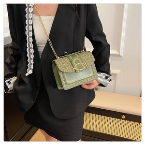 Détail d'un sac à chaîne en tweed vert porté sur un costume noir pour un look élégant
