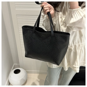 Dettaglio della trama in pelle intrecciata nera e patch logo su una grande borsa tote