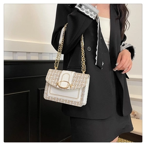 Détail du sac bandoulière en tweed et cuir avec chaîne dorée et boucle ovale en métal