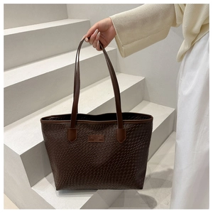 Dettaglio della borsa tote intrecciata marrone scuro con manici sottili in pelle
