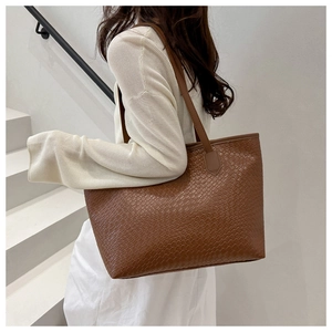 Dettaglio della borsa tote in pelle intrecciata marrone con texture e spallacci robusti