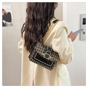Detail of tweed crossbody bag with gold chain strap and U-shaped metal buckle on model
