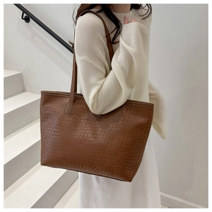 Dettaglio della trama intrecciata e del logo sulla grande borsa tote marrone da donna