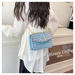 Détail d'un sac en tweed bleu porté à l'épaule dans un décor de café élégant