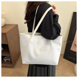Dettaglio di una borsa tote bianca a trama intrecciata con tracolla e marchio