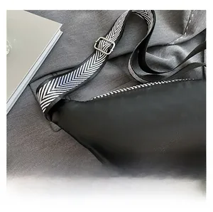 Détail du sac de poitrine en similicuir noir avec texture litchi et bandoulière tissée