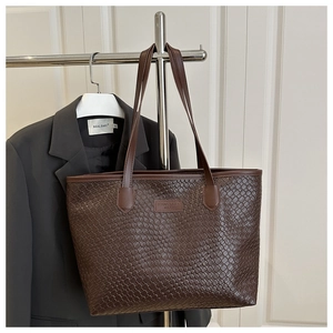 Dettaglio borsa tote in pelle intrecciata marrone scuro con logo e manici a spalla