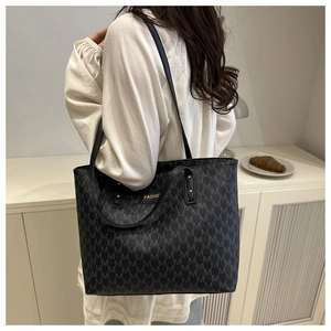 Close-up of a large grey tote bag with M-pattern print and gold fashion metal plaque