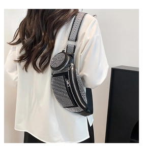 Detail of a black crossbody saddle bag with sparkling rhinestones and wide striped strap