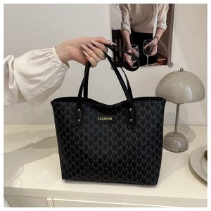 Fashion tote bag with M-letter print and gold logo shown held in a stylish interior