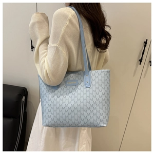 Detail of light blue tote bag with M-pattern monogram and gold Fashion metal plaque