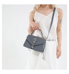 Gray textured crossbody bag with gold hardware and chain strap on white dress model