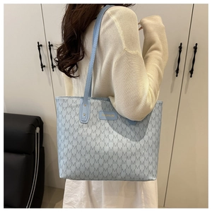 Detail of light blue tote bag with navy M pattern and golden fashion logo plaque
