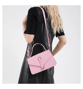 Detailed back view of a pink textured crossbody bag with a gold metal clasp lock