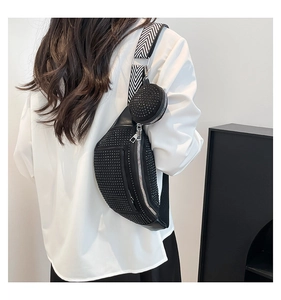 Close-up of black rhinestone crossbody bag with woven strap and small round pouch