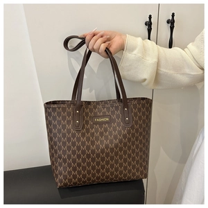 Close-up of brown monogram tote bag with gold-tone fashion plate and long leather handles