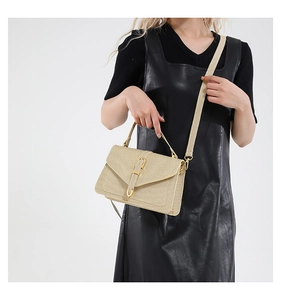 Detail of woven textured crossbody bag with gold buckle on black leather dress