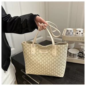 Close-up of a large tote bag featuring m-pattern prints and fashion leather patch detail
