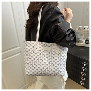 Detailed side view of high-capacity tote bag with all-over M print and fashion label
