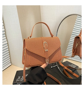 Detail of orange woven texture handbag with metal buckle and detachable strap