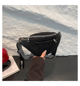 Detail of black rhinestone chest bag with herringbone strap and silver hardware