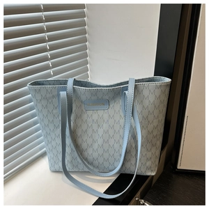 Close-up of light blue tote bag with jacquard M pattern and gold Fashion patch