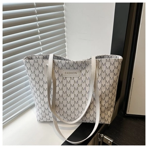 Detail view of large tote bag with M-pattern jacquard and leather brand plaque