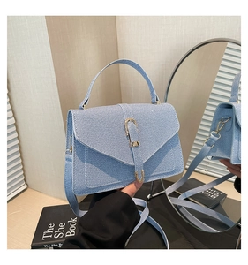 Close-up of light blue denim texture handbag with golden horseshoe buckle and strap