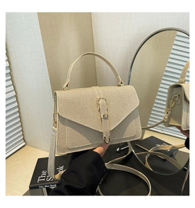 Detail of the woven texture and vertical metal buckle on the light brown crossbody bag
