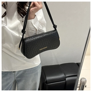 Détail du sac porté épaule tressé noir avec texte doré et bandoulière à nœuds décoratifs