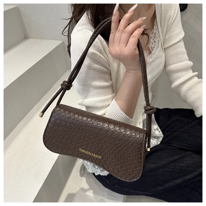 Détail du sac sous le bras marron foncé avec texture tressée, logo doré et bandoulière nouée