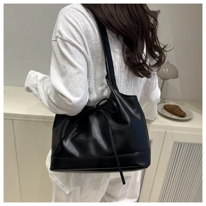 Détail d'un sac cabas en cuir ciré noir montrant sa texture souple et son nœud