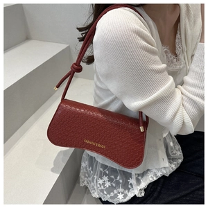 Détail du sac baguette croissant rouge foncé avec motif crocodile et lettrage doré