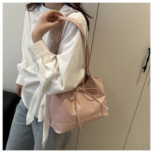 Close-up of a light pink tote bag with a decorative leather bow knot on the shoulder strap