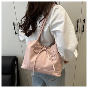 Close-up of pink leather tote bag with elegant bow detail on the shoulder strap