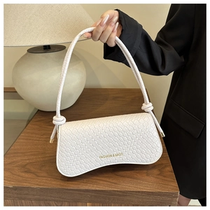 Détail du sac à bandoulière blanc tissé avec poignée nouée et lettrage doré chic