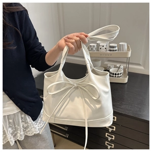 Detail of white mini handbag with a large bow decoration and matte leather texture