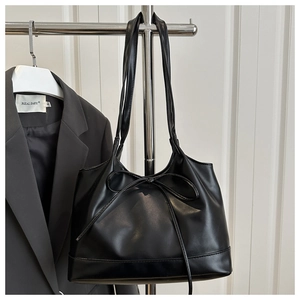 Détail d'un grand sac cabas noir en similicuir avec un nœud décoratif et une finition lisse