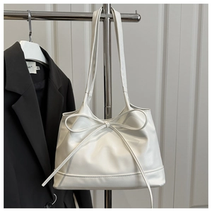 Gros plan détaillé d'un sac en cuir blanc avec un nœud décoratif discret devant