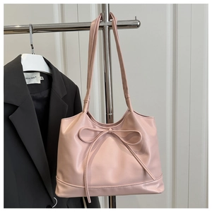 Détail d'un sac cabas rose avec nœud décoratif suspendu pour aperçu de la taille
