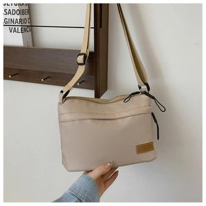 Macro view of beige nylon crossbody bag with zipper compartments and adjustable strap