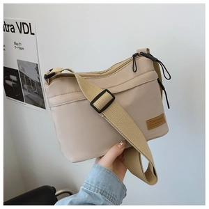 Détail du sac bandoulière beige en nylon avec sangle réglable et logo de mode