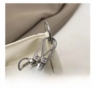 Close-up of high-quality silver metal hooks and zipper on white leather shoulder bag